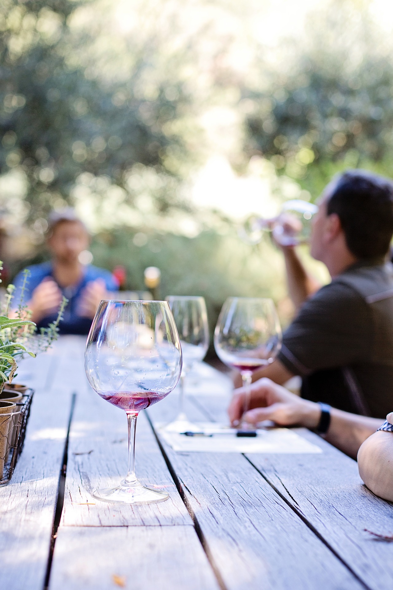 Menschen und Weingläser draußen an einem Tisch