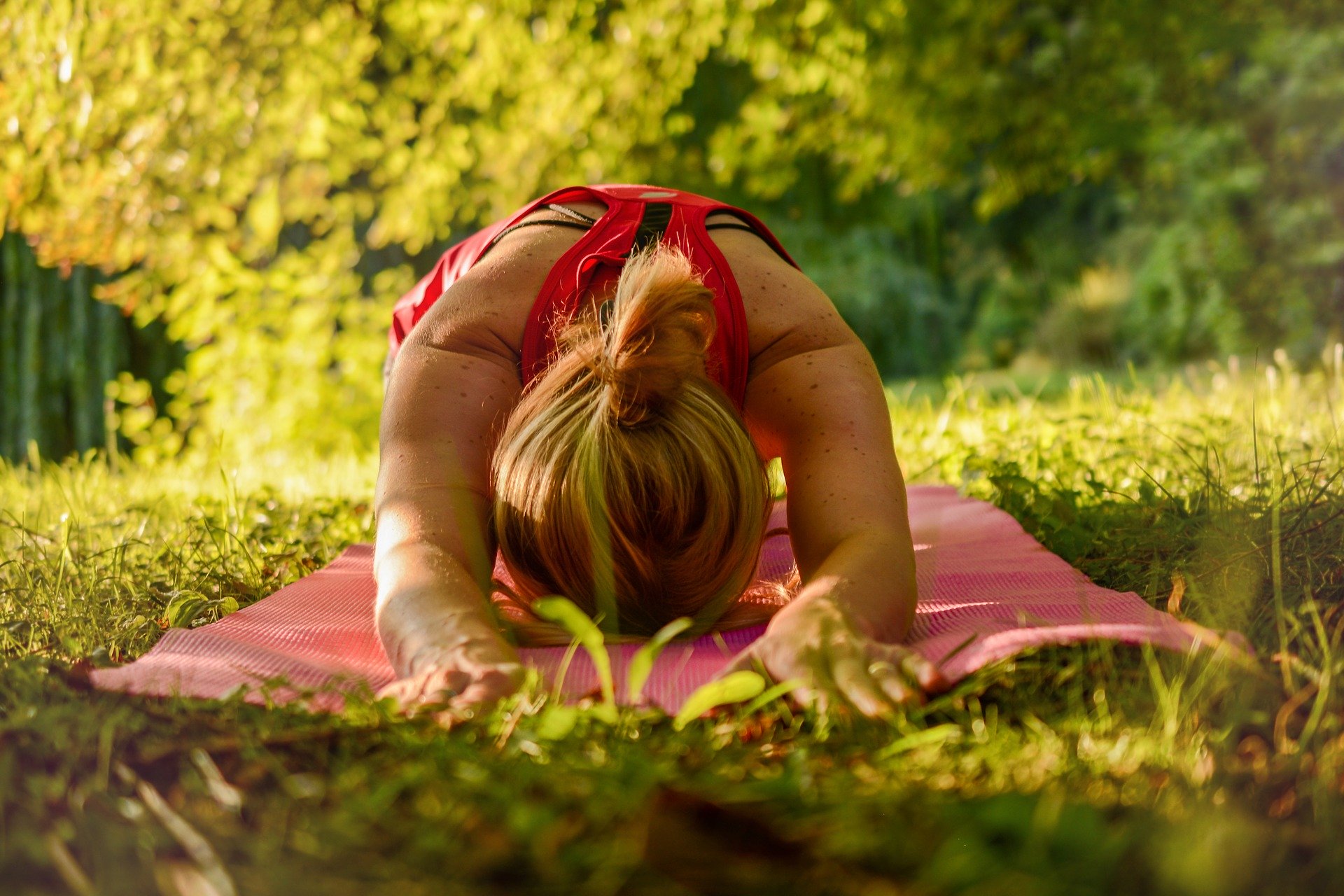 Frau in Yoga Position auf einer Wiese