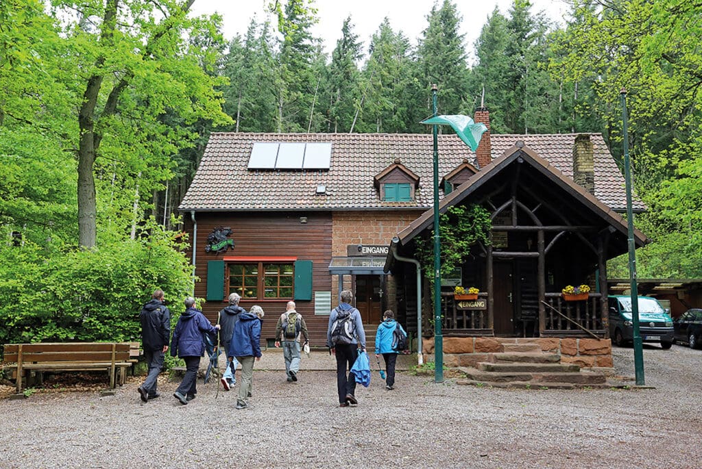 Wanderer laufen auf den Eingang der Landauer Hütte zu