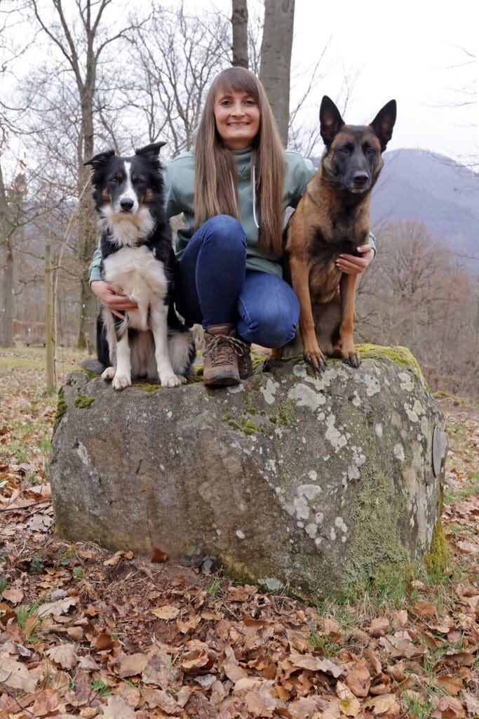 Lea Zimmer sitzt mit ihren Hunden Anni und Saru auf einem Stein